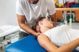 A chiropractor gently adjusting a patient's back in a clinical setting.